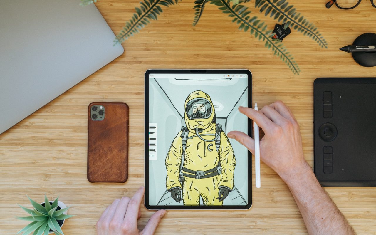 a man drawing on ipad on desk